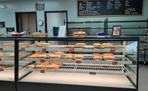 A display case filled with various baked pies and pastries in a cozy bakery setting.