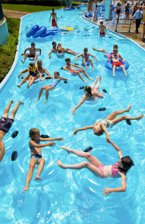 Aerial view of children floating on inner tubes in a water park's lazy river, enjoying a sunny day.