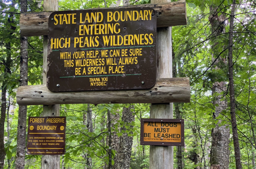 Sign marking the entrance to High Peaks Wilderness, stating rules and thanking visitors for their cooperation.