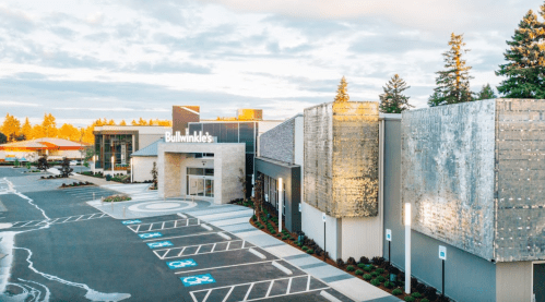 Exterior view of a modern building with a sign reading "Bullwinkle's," surrounded by landscaped parking and trees.