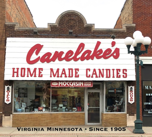Storefront of Canelake's Homemade Candies in Virginia, Minnesota, featuring a vintage sign and display of candy products.