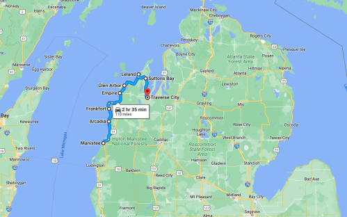 Map of northern Michigan showing locations like Traverse City, Suttons Bay, and Glen Arbor with travel time indicated.