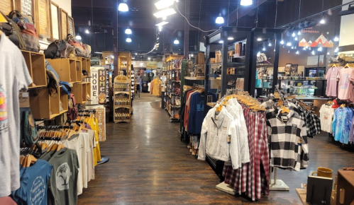 A spacious retail store aisle lined with clothing racks and shelves filled with various merchandise.
