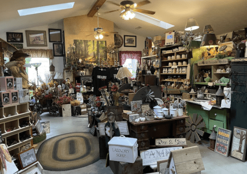 A cozy shop filled with rustic decor, crafts, and home goods, featuring wooden shelves and various decorative items.