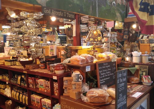 A cozy market display filled with various food items, jars, and rustic decor, featuring a sign that says "God Accepts U Turns."