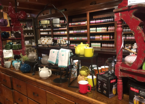 A cozy shop display featuring colorful teapots, mugs, and kitchenware on wooden shelves and tables.