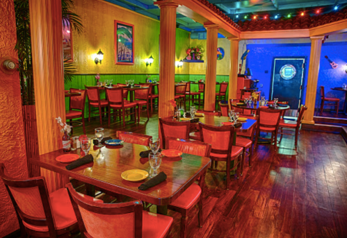 Colorful restaurant interior with wooden tables, red chairs, and vibrant walls, creating a lively dining atmosphere.