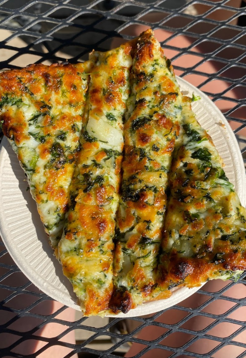 Three slices of cheesy garlic bread topped with herbs, served on a paper plate.