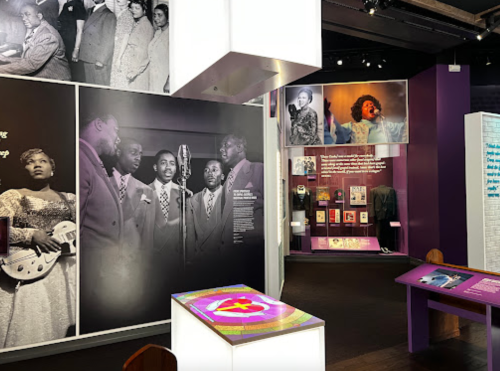 Exhibit showcasing historical figures in music, featuring photos, artifacts, and interactive displays in a vibrant setting.