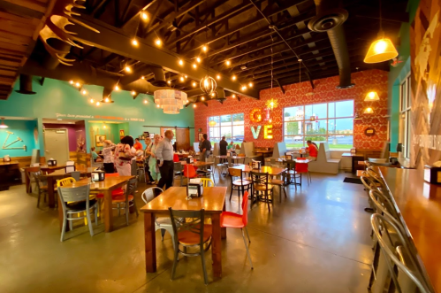 A vibrant restaurant interior with colorful decor, wooden tables, and patrons enjoying their meals under warm lighting.
