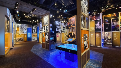 A vibrant museum exhibit featuring colorful panels, photographs, and interactive displays in a well-lit space.