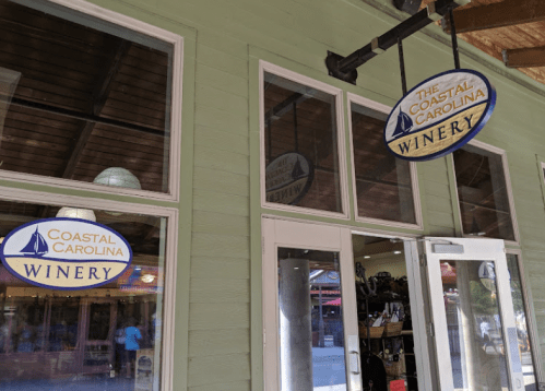 Exterior of Coastal Carolina Winery with signs above double doors and a wooden ceiling.