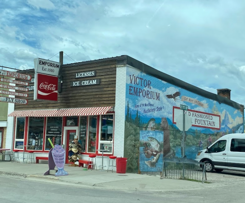 A colorful emporium with a vintage ice cream sign and a mural, featuring a classic soda fountain and outdoor seating.