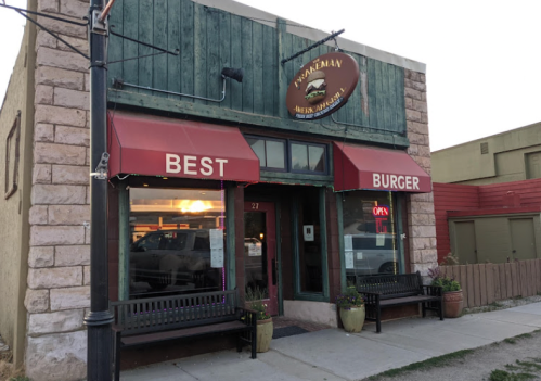 Exterior of a rustic burger restaurant with red awnings, a sign reading "Best Burger," and a welcoming entrance.