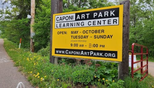 Sign for Caponi Art Park Learning Center, open May to October, Tuesday to Sunday, 9 AM to 2 PM, closed Monday.