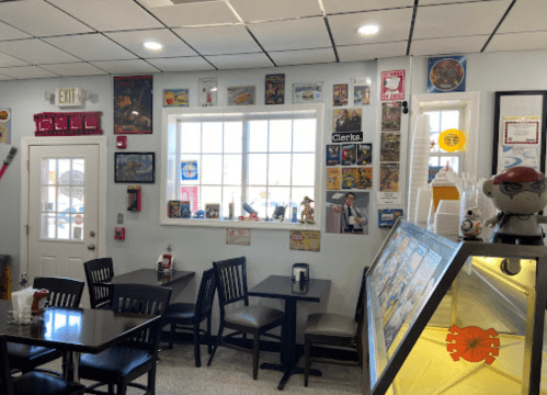 A cozy diner interior with black chairs, a window, and walls decorated with vintage posters and memorabilia.