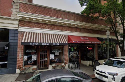 Exterior view of a restaurant with striped awnings, featuring "Bamyan Afghan Cuisine" and a neighboring pizza place.