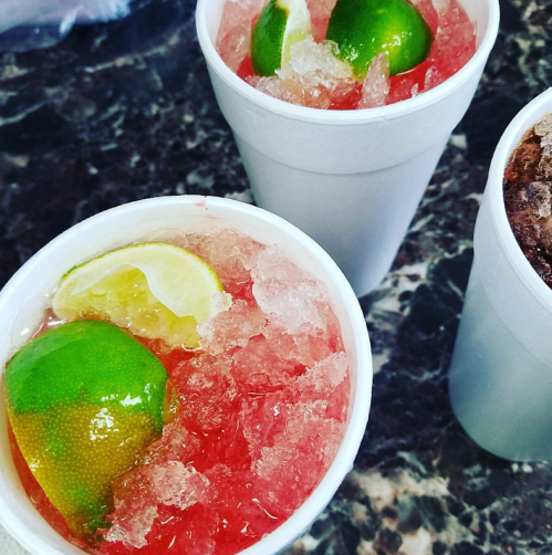 Three white cups filled with crushed ice and colorful drinks, garnished with lime and lemon slices.