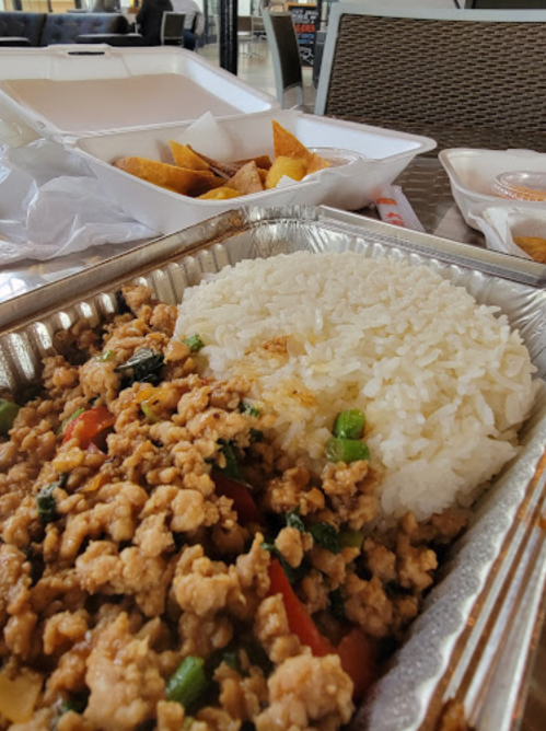 A close-up of a meal featuring stir-fried ground meat with vegetables and a side of white rice, with chips in the background.