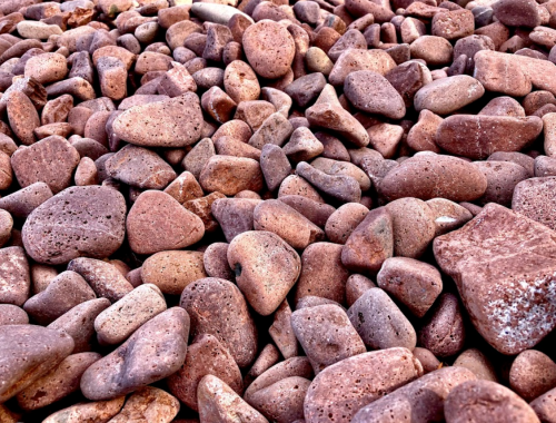 A close-up view of a variety of smooth, rounded stones in shades of brown and gray, scattered across a surface.