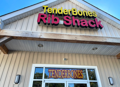 Sign for "TenderBones Rib Shack" on a light-colored building with large, colorful letters.