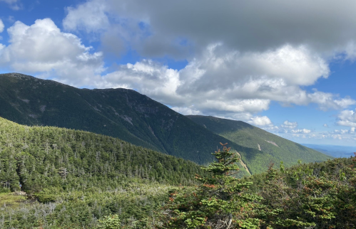 A scenic view of mountains covered in greenery under a partly cloudy sky.