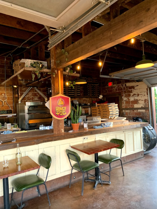 Cozy restaurant interior with wooden beams, a counter, tables, and a cactus, featuring a sign for "Honey Pie."