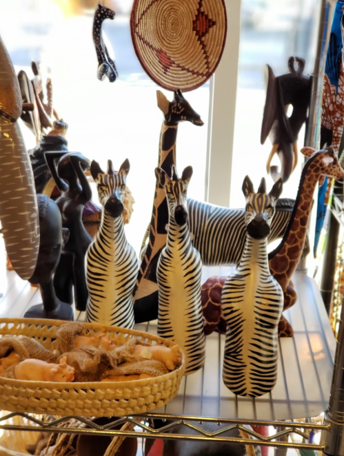 A display of decorative animal figurines, including striped zebras and giraffes, in a bright shop window.