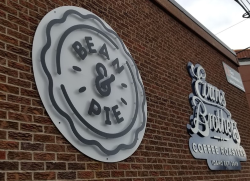 Signage for "Bean & Pie" and "Evans Brothers Coffee Roasters" on a brick wall.