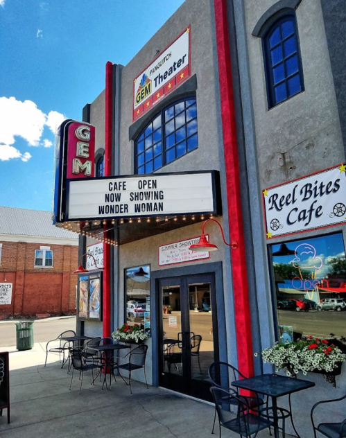 Exterior of the Gem Theater with a marquee displaying "Now Showing: Wonder Woman" and a cafe open sign.