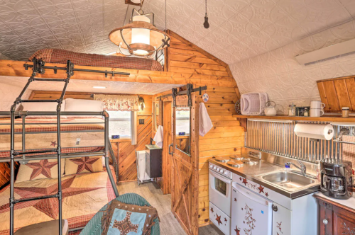 Cozy interior of a rustic cabin with a bunk bed, kitchenette, and wooden decor. Warm and inviting atmosphere.