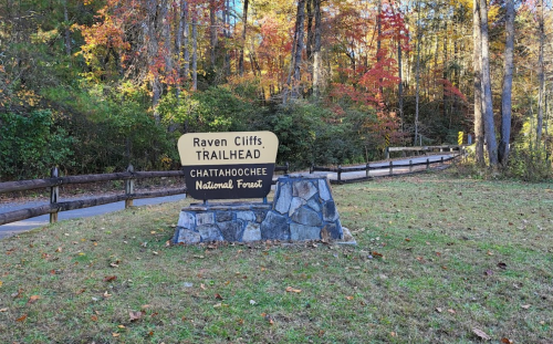 Sign for Raven Cliffs Trailhead in Chattahoochee National Forest, surrounded by trees and autumn foliage.