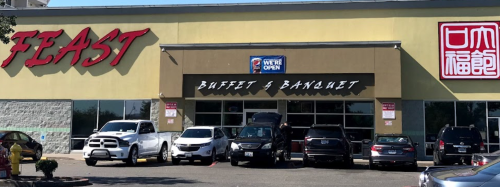 Exterior of a buffet and banquet venue named "Feast," with several cars parked in front and a sign indicating it's open.