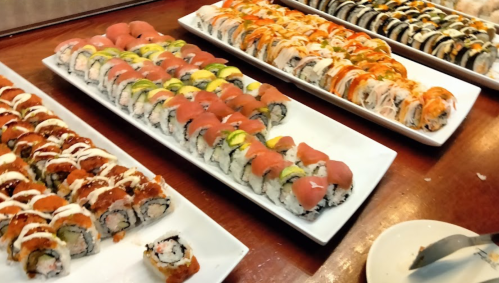 A variety of colorful sushi rolls arranged on white platters, showcasing different ingredients and styles.