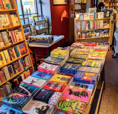 A cozy bookstore interior with shelves of books and a table displaying a variety of colorful book covers.