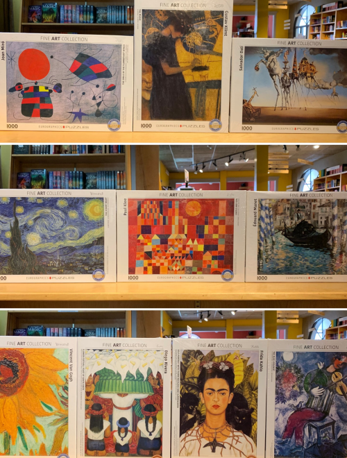A display of fine art collection puzzles featuring famous artworks on shelves in a bookstore.