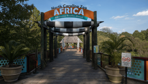 Entrance to the Africa section of the North Carolina Zoo, featuring a colorful sign and lush greenery.