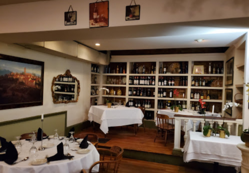 Cozy restaurant interior with tables set for dining, wine shelves, and decorative artwork on the walls.