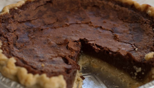 A chocolate pie with a slice removed, showcasing a rich, cracked top and a flaky crust.