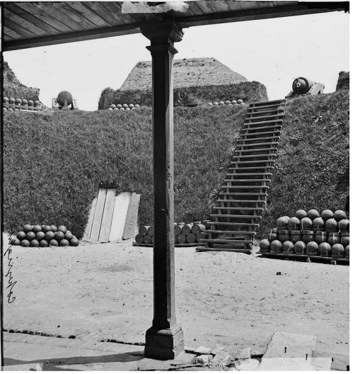 A historic black-and-white photo showing a staircase leading up to grassy mounds, with stacked cannonballs on either side.