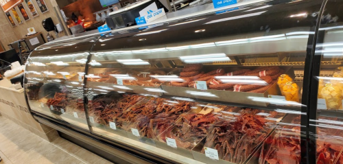 A display case filled with various types of jerky and cured meats in a store.