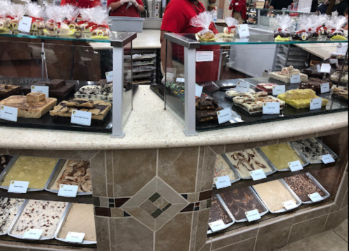 Display of assorted desserts and confections in a bakery, with various treats labeled on the counter.