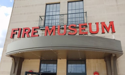 Signage of a Fire Museum, featuring bold red letters against a light-colored building facade.