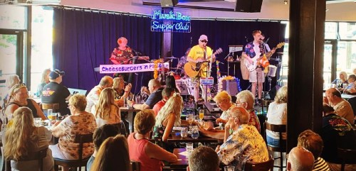 A lively restaurant scene with a band performing on stage while guests enjoy their meals and drinks.