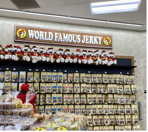 A display of various jerky bags under a sign that reads "World Famous Jerky," with stuffed animals on top.