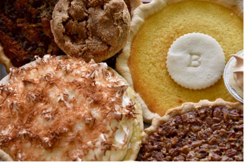 A variety of pies and cookies, including pecan, coconut cream, and a yellow cake with a decorative "B" on top.