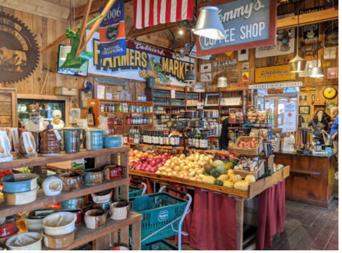 A cozy market interior with wooden decor, shelves of jars, fresh produce, and a coffee shop sign.