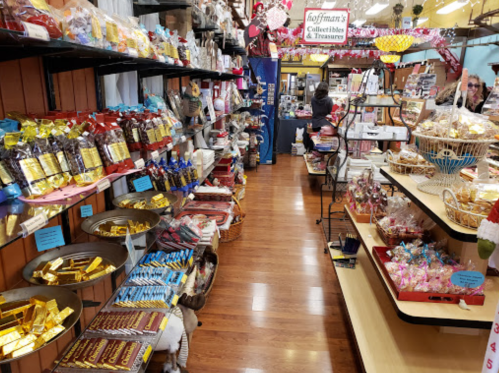 A colorful shop aisle filled with various candies, chocolates, and treats displayed on shelves and tables.