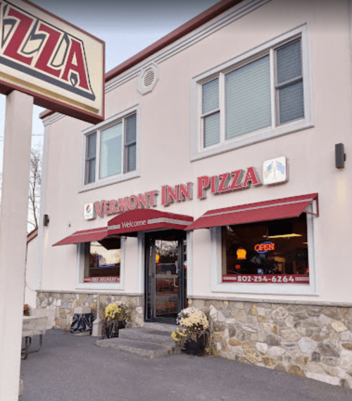 Exterior of Vermont Inn Pizza, featuring a welcoming entrance, stone facade, and red awning with "Open" sign.