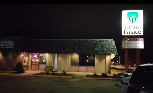 Exterior of China Palace restaurant at night, featuring a lit sign and a darkened building with large windows.